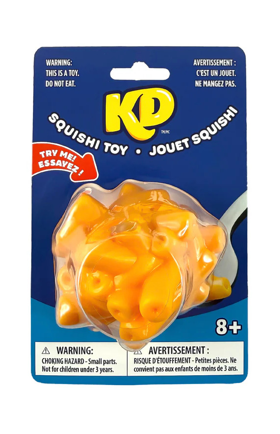 Kraft Dinner branded squishy toy in retail blister packaging, shaped like a scoop of macaroni and cheese with a clear DO NOT EAT warning